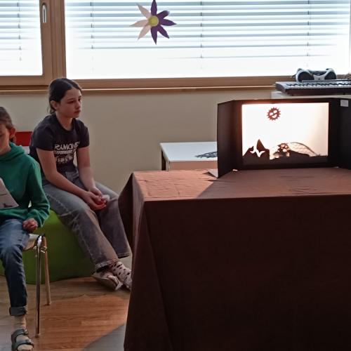 2 Mädchen sitzen neben dem Schattentheater und lesen