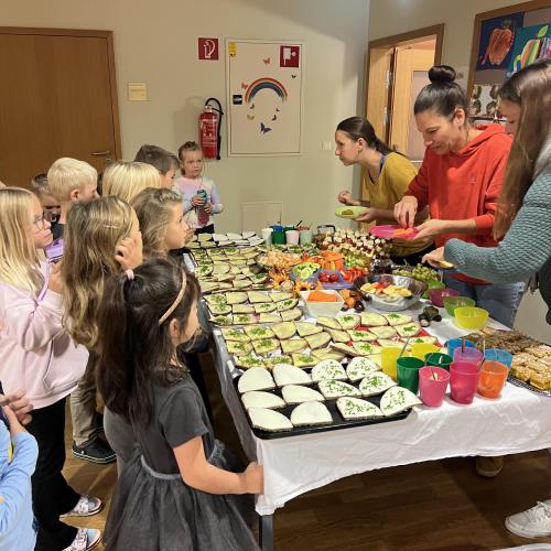 Kinder stehen am Buffet und werden von den Müttern bedient.