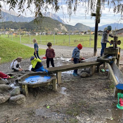 Die Kinder spielen bei der Wasserstelle.