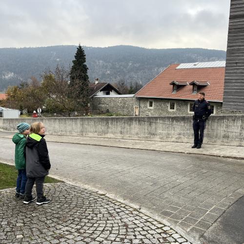 Zwei Kinder stehen an der Straße, Polizist ist auf anderer Straßenseite