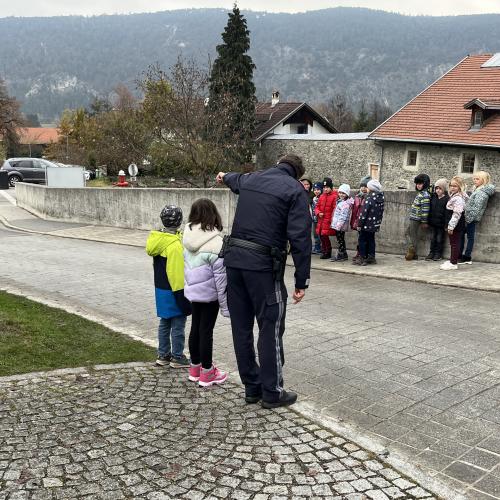 Polizist weist zwei Kinder auf die Gefahren der Straße hin