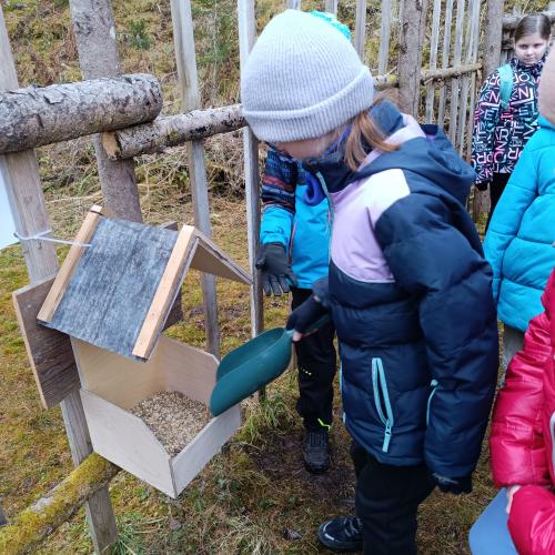 Kinder befüllen das Futterhäuschen 