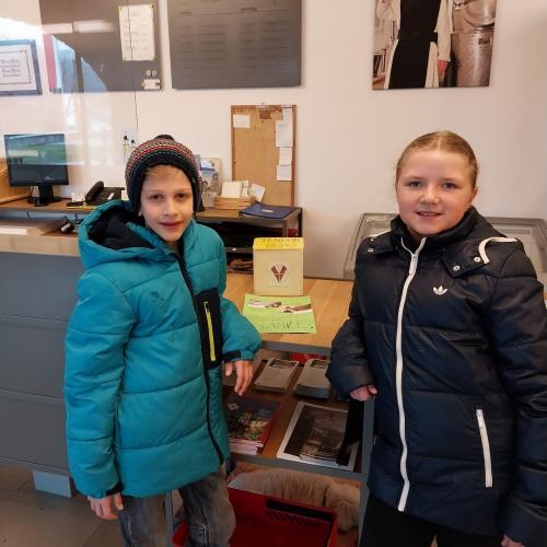 Mädchen und Bub mit Spendenbox in der Bücherei