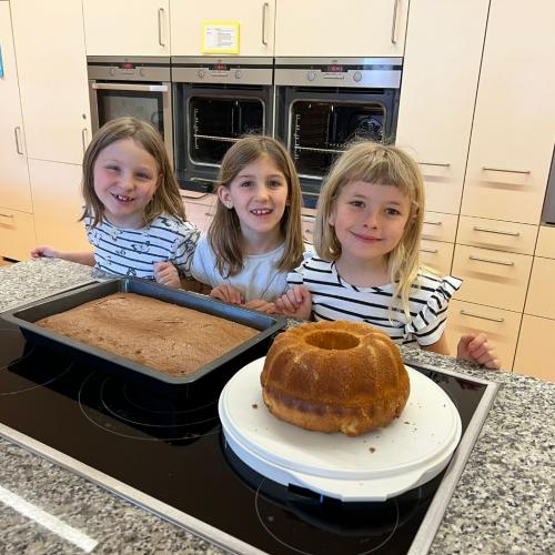 3 Mädchen zeigen stolz ihren selbstgebackenen Kuchen