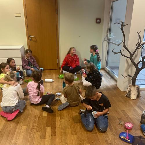 Kinder sitzen zusammen am Boden und jausnen