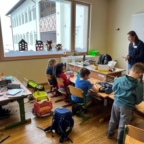 Eine Erzählerin erklärt einem Mädchen die Aufgabe, andere Kinder arbeiten