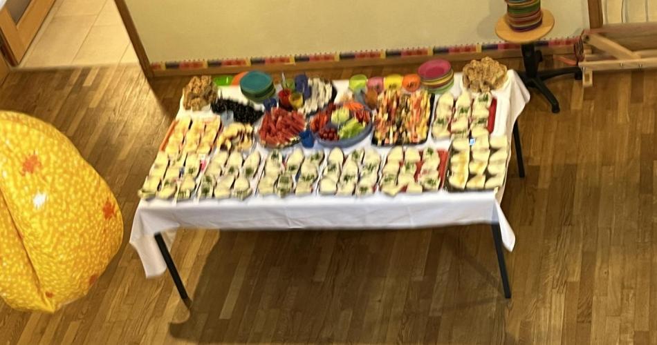 Tisch mit Broten, Obstsalat, Gemüse, Kuchen